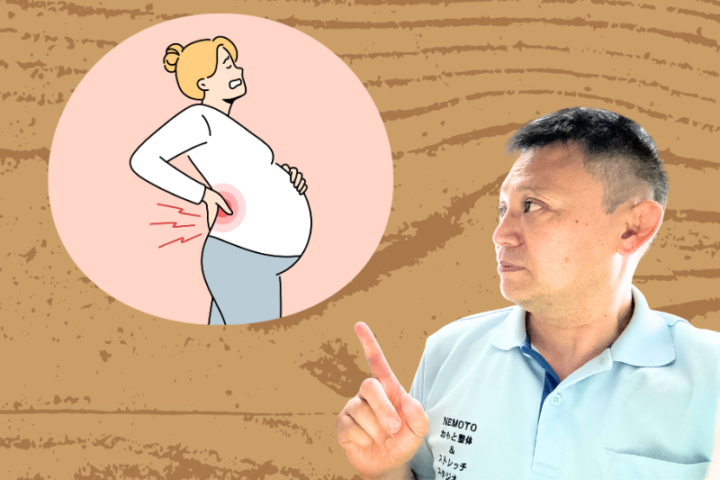 医療従事者が妊婦の腰痛について説明している様子。がねもと整体&ストレッチスタジオ根本院長が、腰に手を当てて痛みを感じている妊婦のイラストを指差している。イラストの妊婦は白いトップスとグレーのボトムスを着用し、腰部に赤い線で痛みが表現されている。